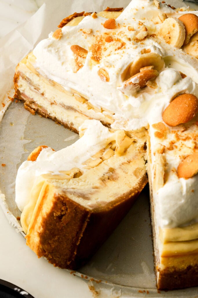 slice of banana pudding cheesecake laid down next to the whole cheesecake
