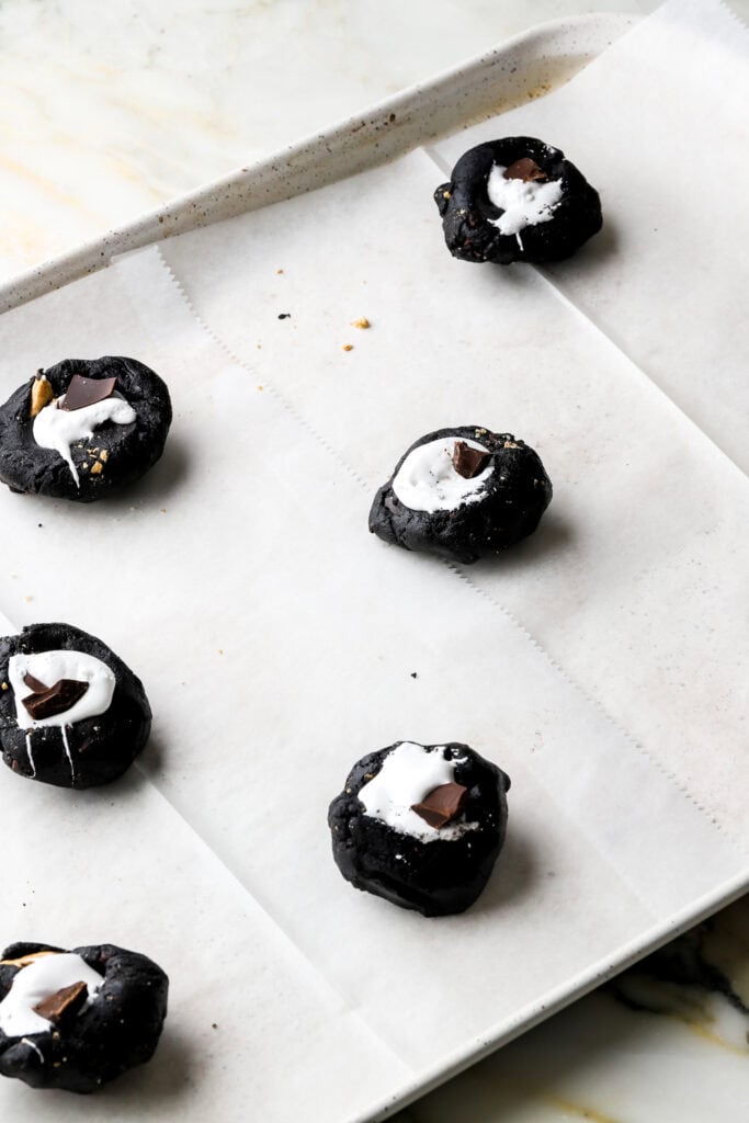chocolate s'mores cookie dough rolled into balls with a well in the center filled with marshmallow fluff