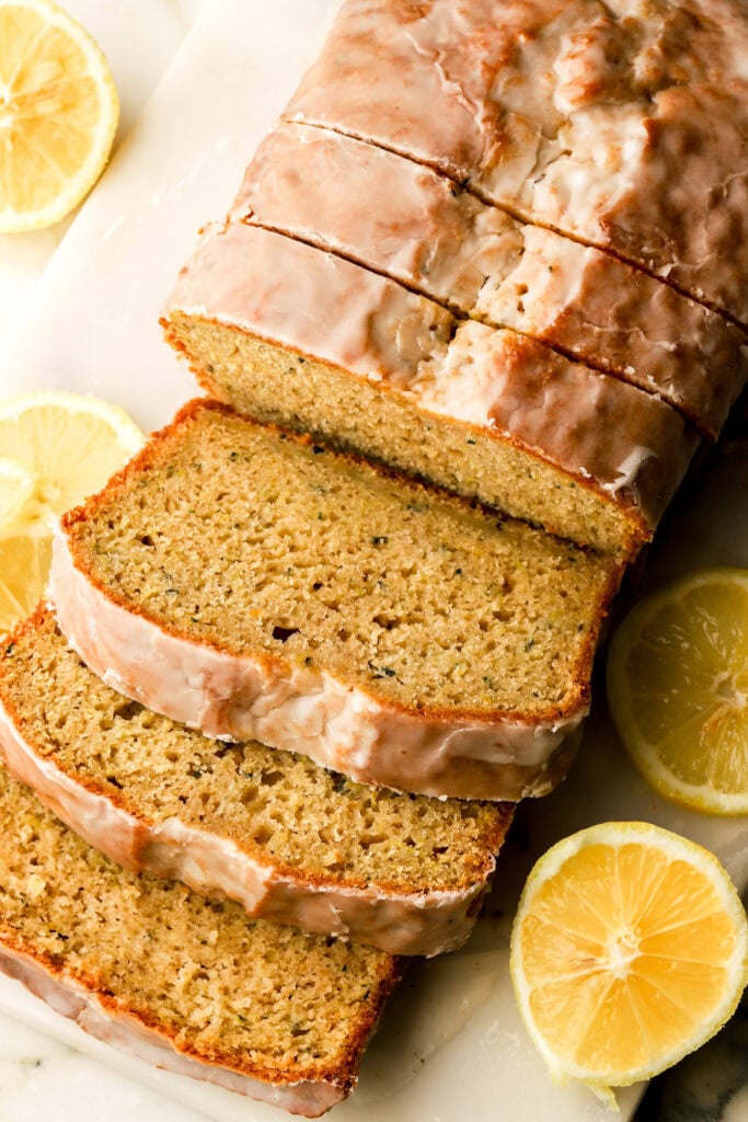 lemon zucchini bread with lemon glaze sliced on a cutting board