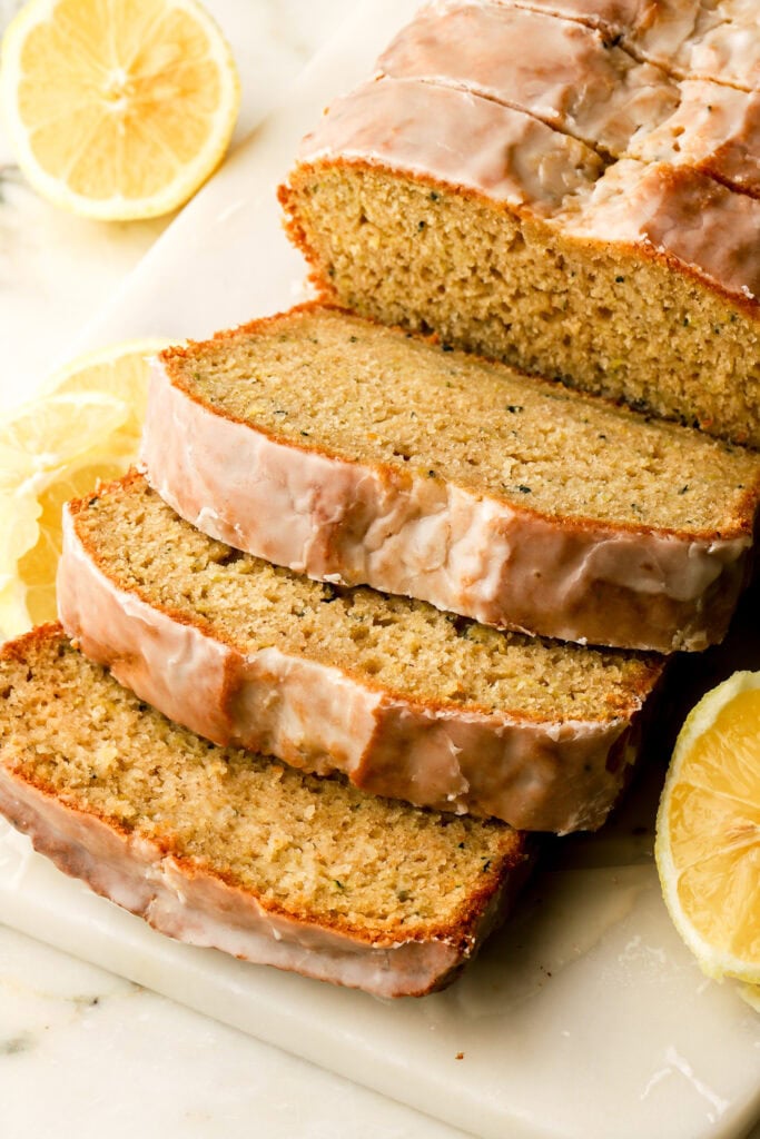 lemon zucchini bread with lemon glaze sliced on a cutting board