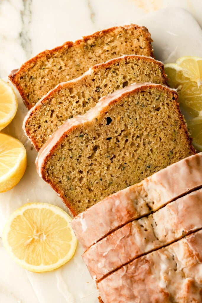 lemon zucchini bread with lemon glaze sliced on a cutting board