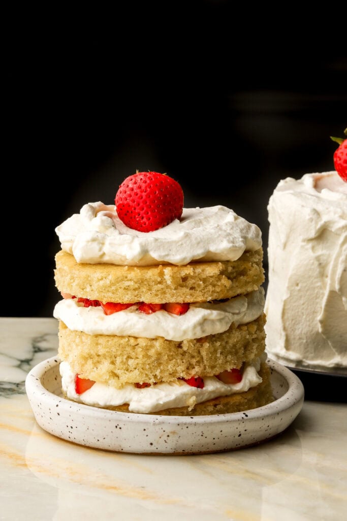mini vanilla cake left naked with layers of vanilla cake, chantilly cream/whipped cream and strawberry chunks