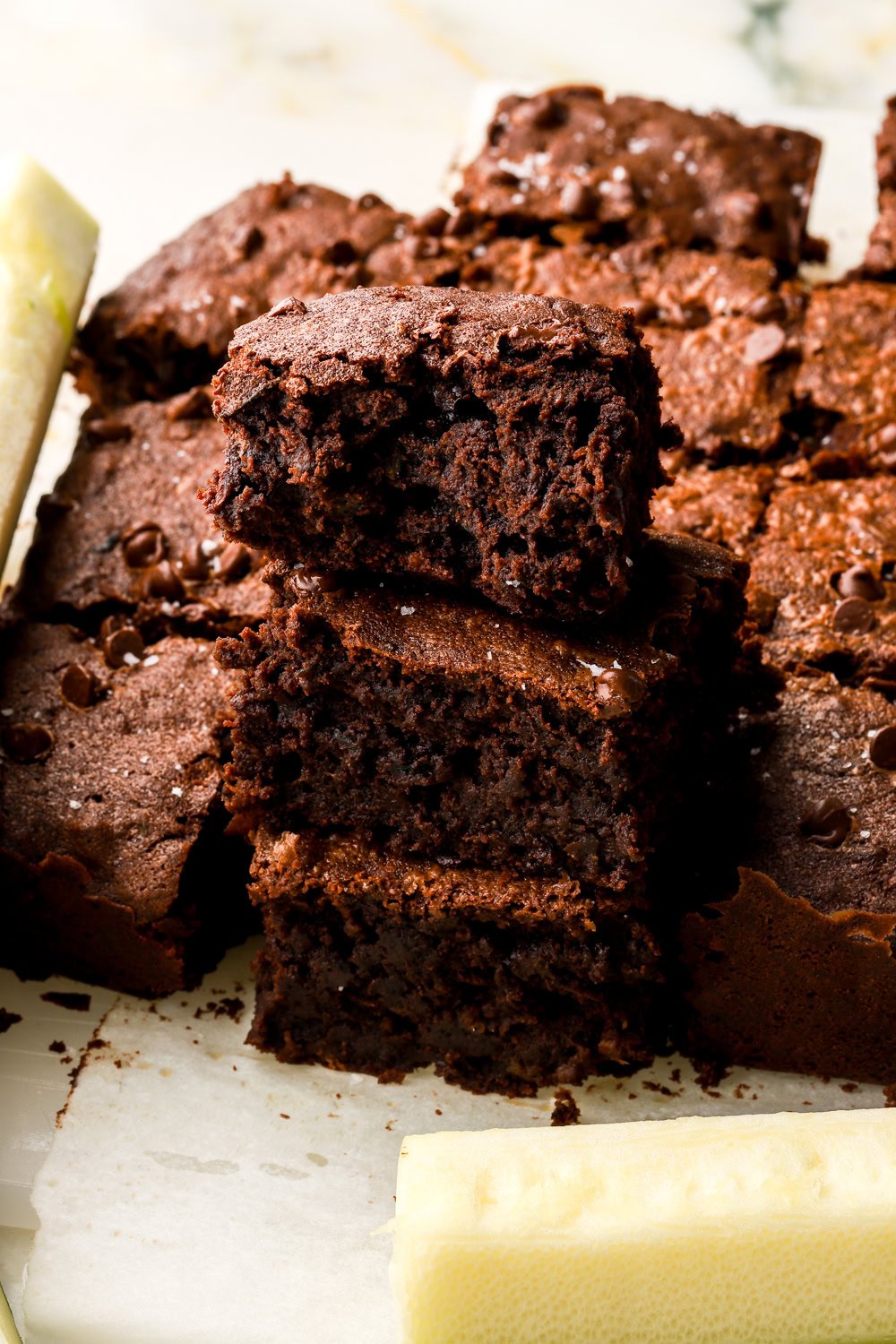 Stack of three zucchini brownies with a sliced zucchini next to it