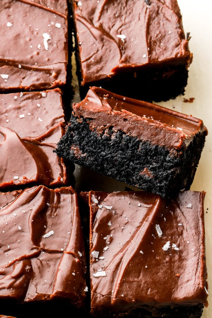 black cookie bars frosted with chocolate frosting, sliced and one showing the inside