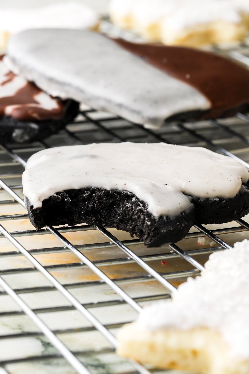 Close up shot of a black cocoa sugar cookie cut into a heart and frosted with white icing