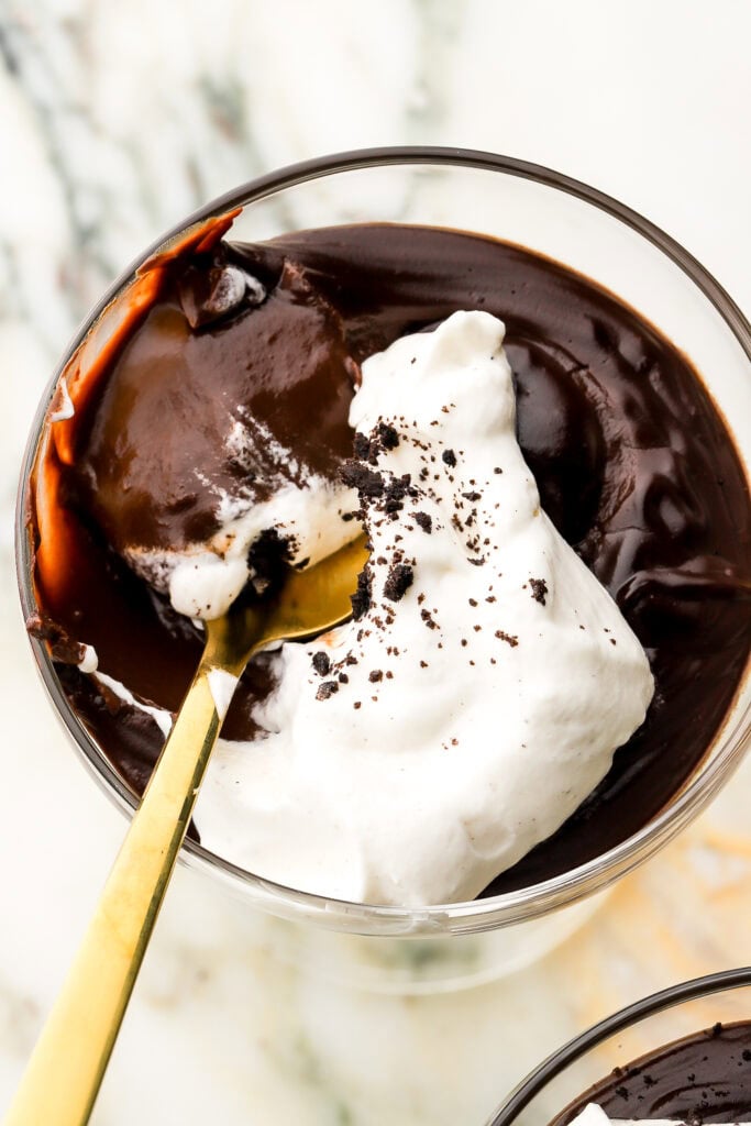 close up of chocolate pudding in a coupe glass topped with whipped cream