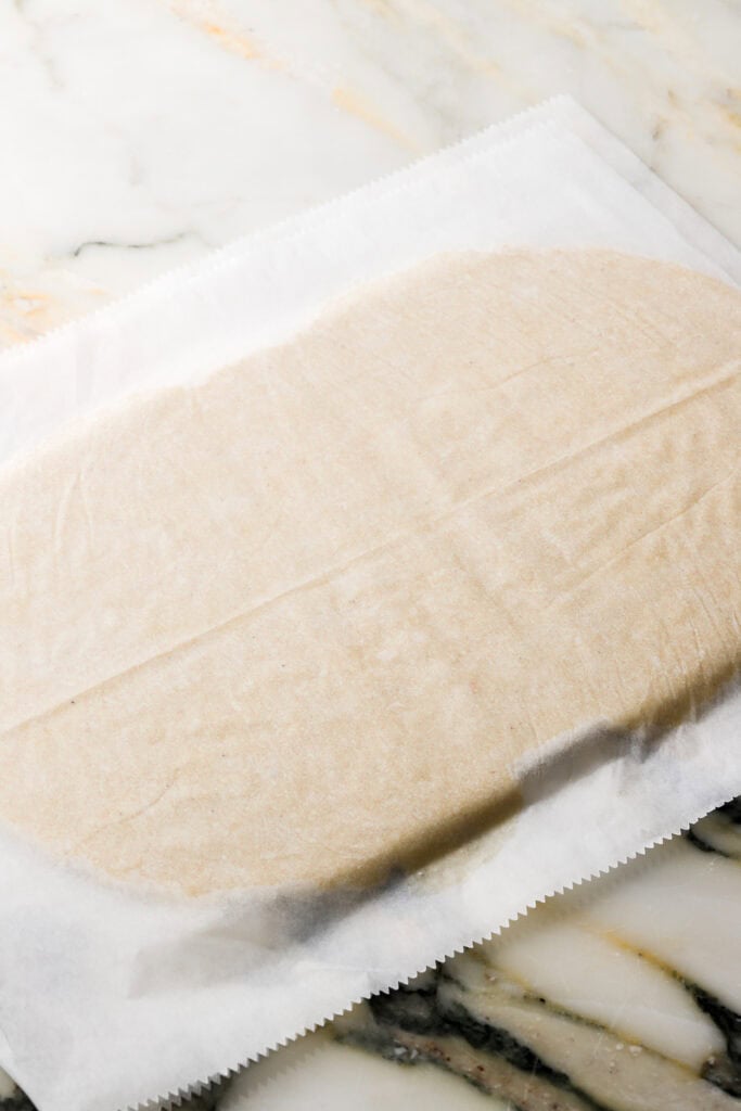 cookie dough rolled out between two sheets of parchment paper