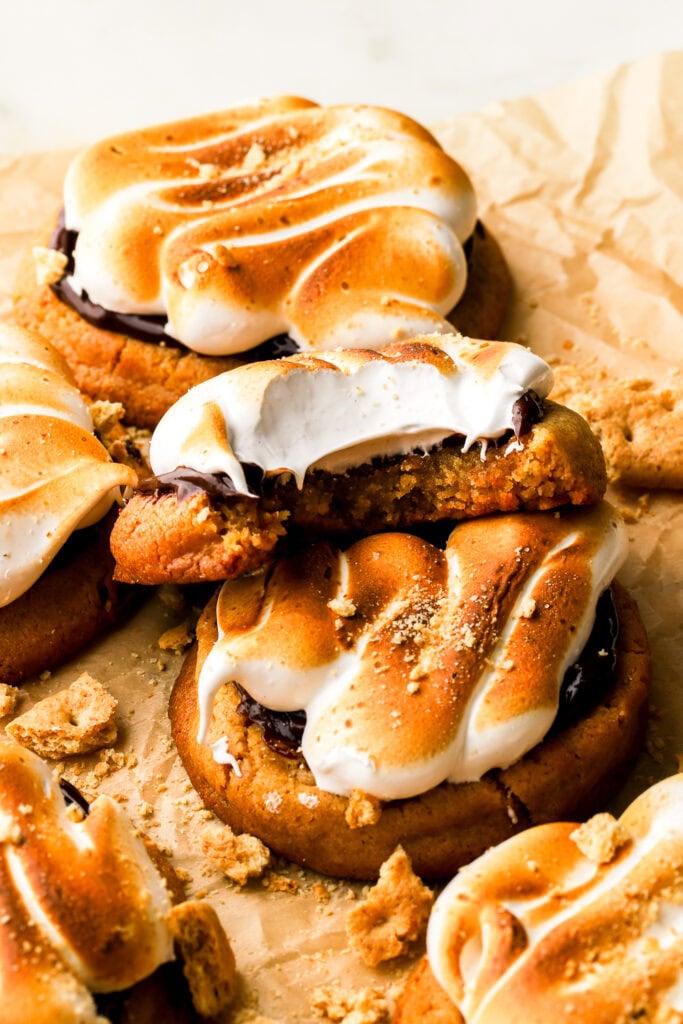 frosted s'mores cookies on a parchment paper with bite taken out of one