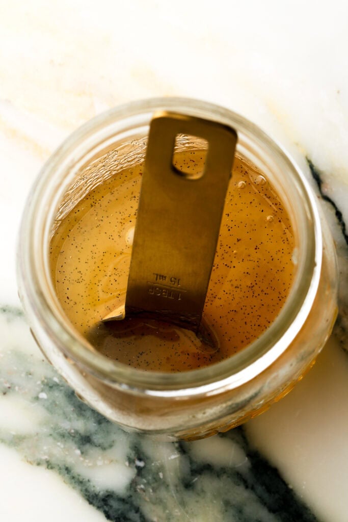 almond syrup poured into a jar with a measuring spoon