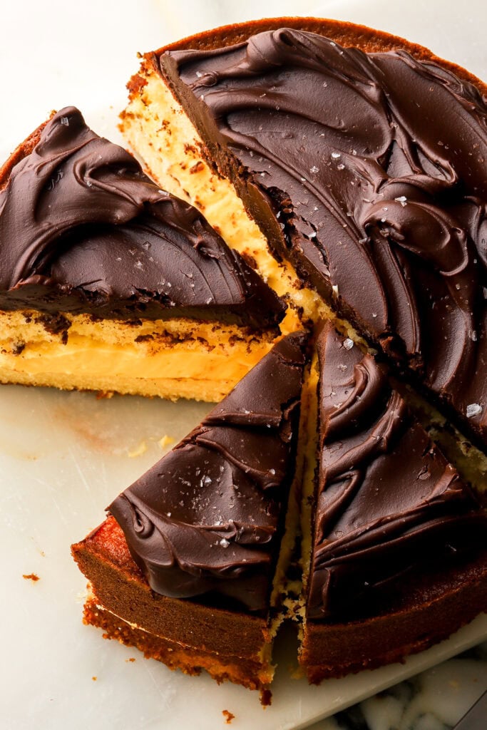 overhead shot of sliced boston cream pie topped with a swirl of chocolate ganache on top