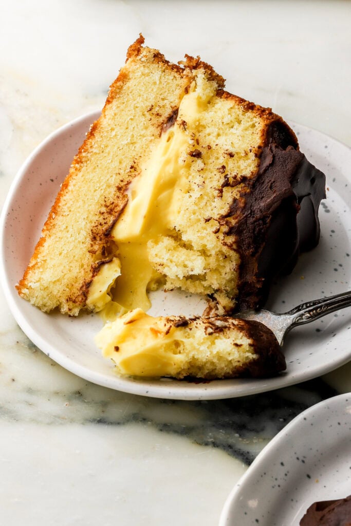 slice of boston cream pie on a plate with a bite taken out