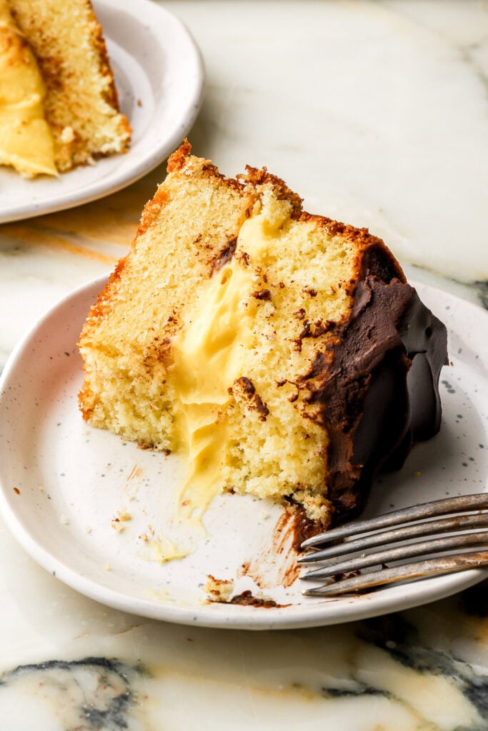 slice of boston cream pie on a plate with a couple bites taken out