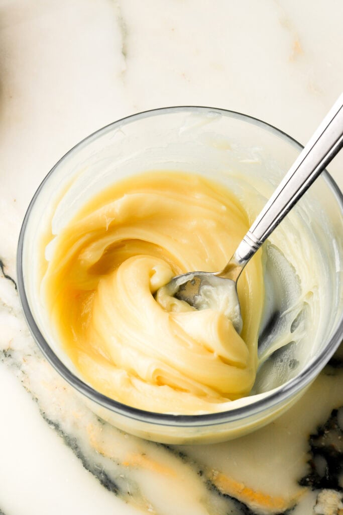 white chocolate ganache cooled and spreadable in a bowl with a spoon