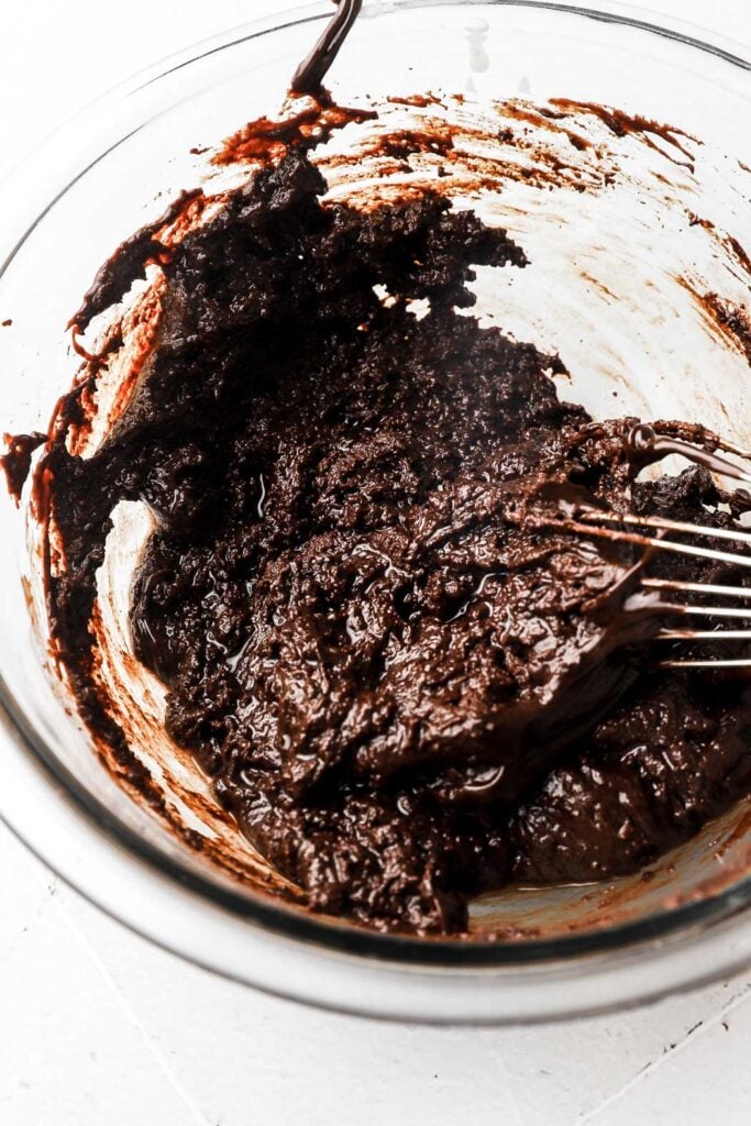 oily and grainy chocolate ganache in a bowl with a whisk