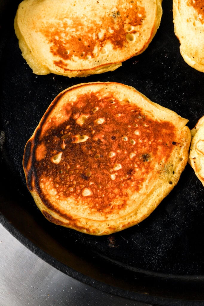 cottage cheese pancakes fully cooked on a cast iron with white chocolate and dark chocolate chips