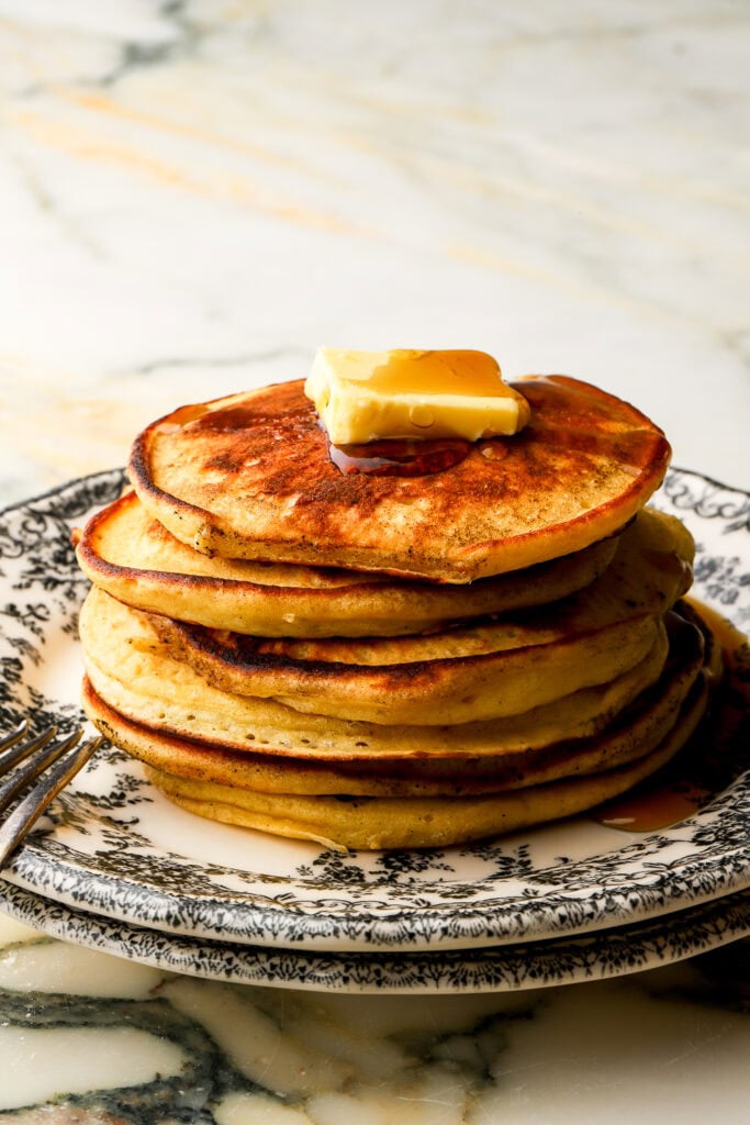 finished pancakes stacked with butter on top and a drizzle of maple syrup
