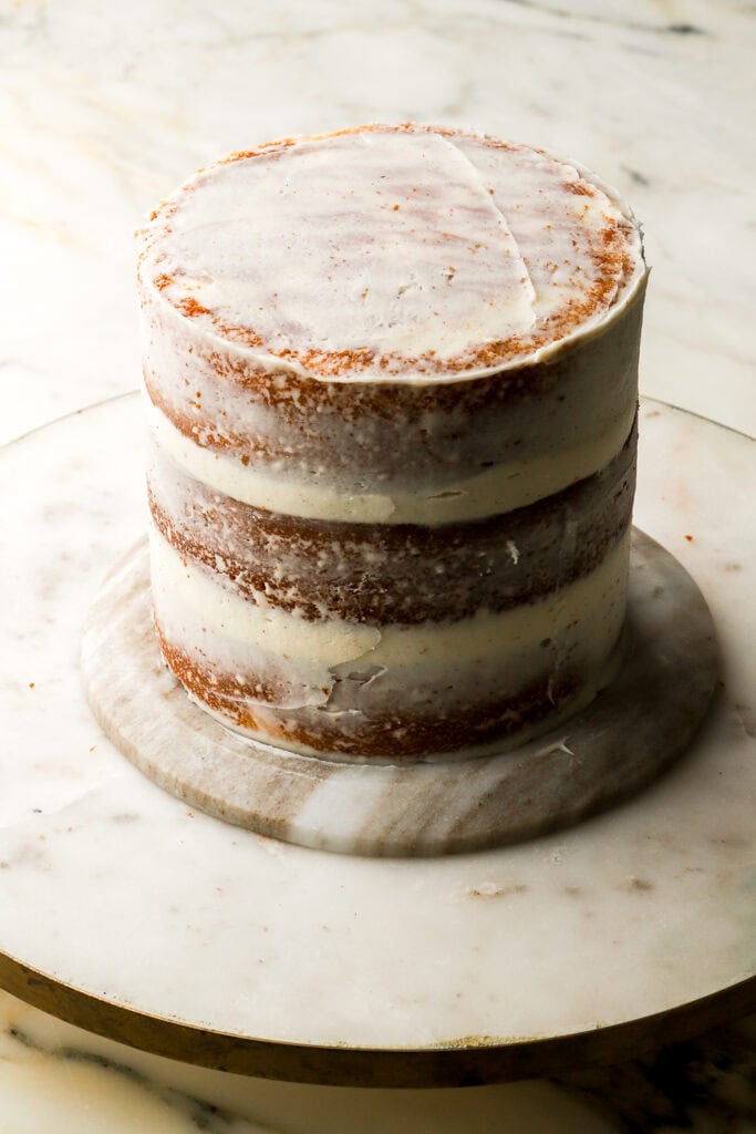 vanilla frosting crumb coat on three layer vanilla cake on marble board