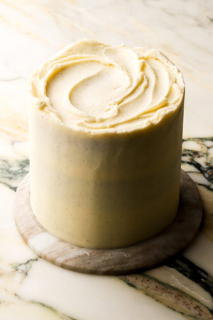 6 inch cake frosted with vanilla american buttercream on marble countertop