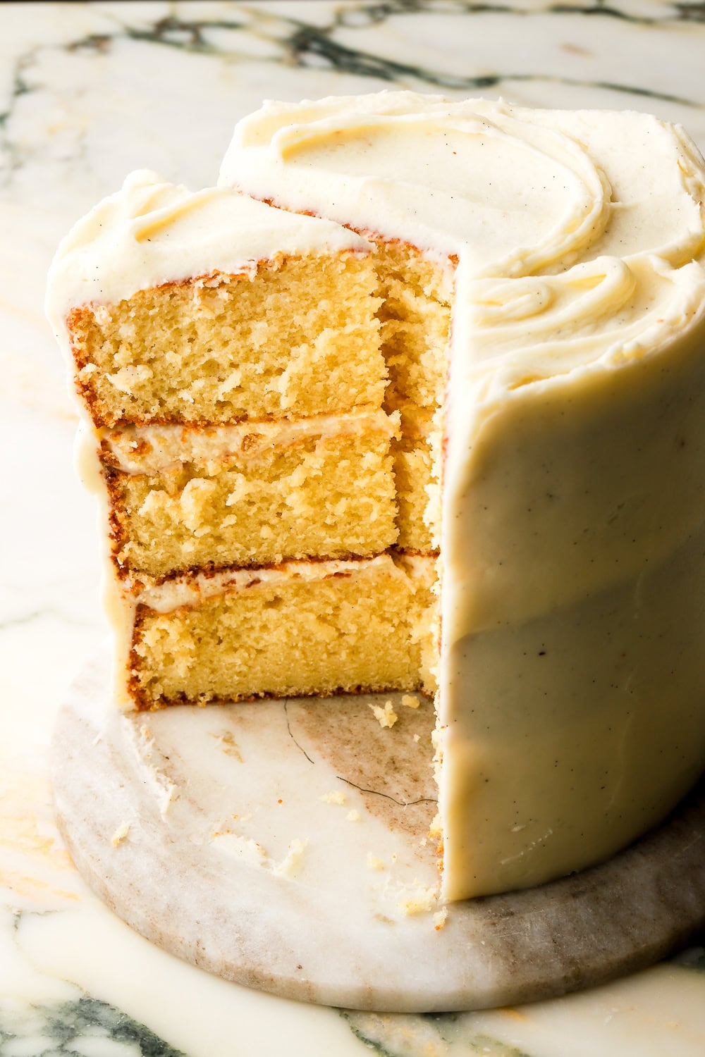three layer vanilla cake with vanilla buttercream sliced and standing tall showing the inside of the cake