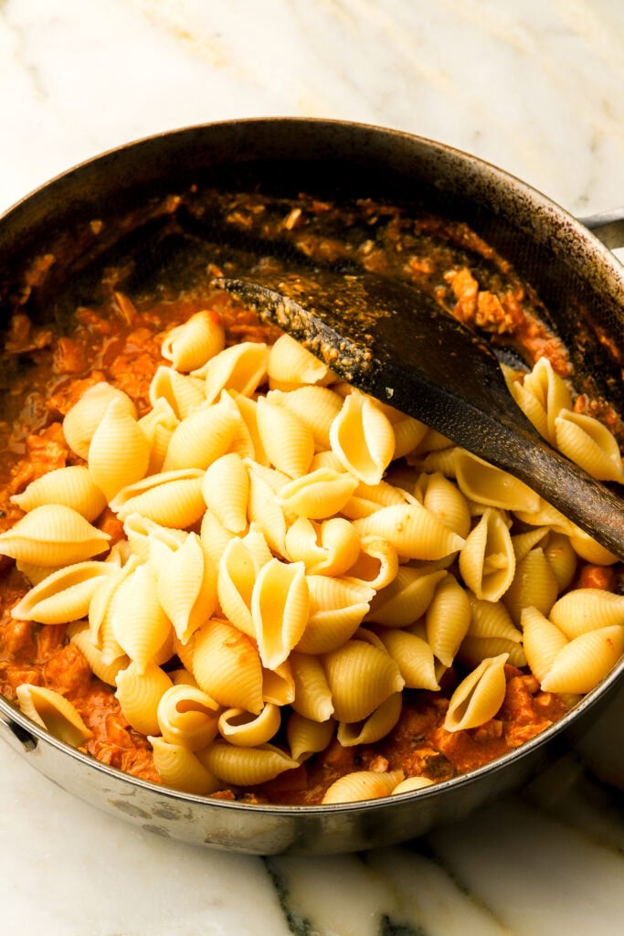 tocanita in a pan and pasta added on top 