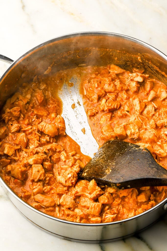 wooden spoon dragging sauce from tocanita in a pan to hold a streak