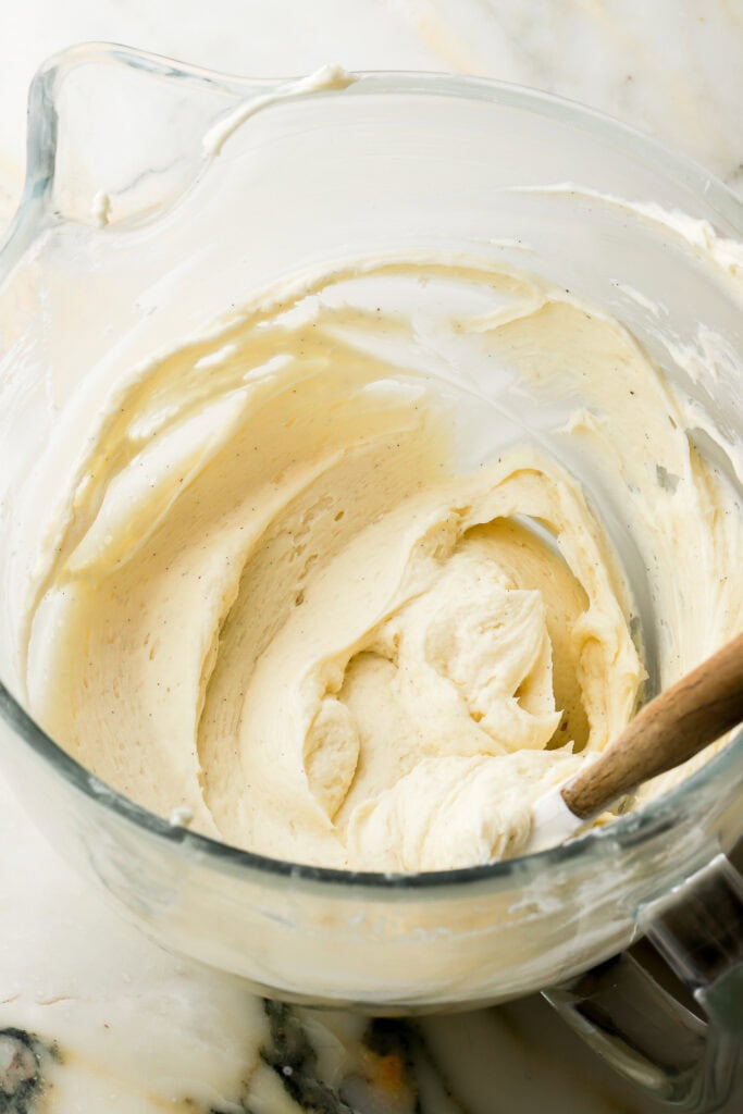 American buttercream swirled in a glass mixer bowl with a rubber spatula