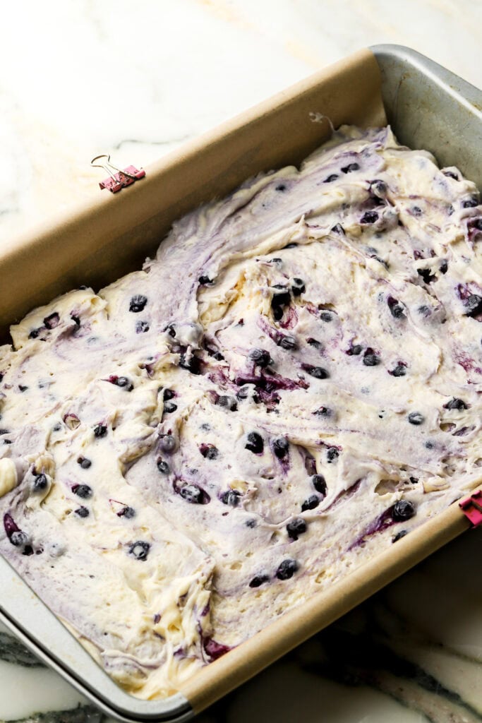 blueberry coffee cake batter spread into a lined 9x13" pan
