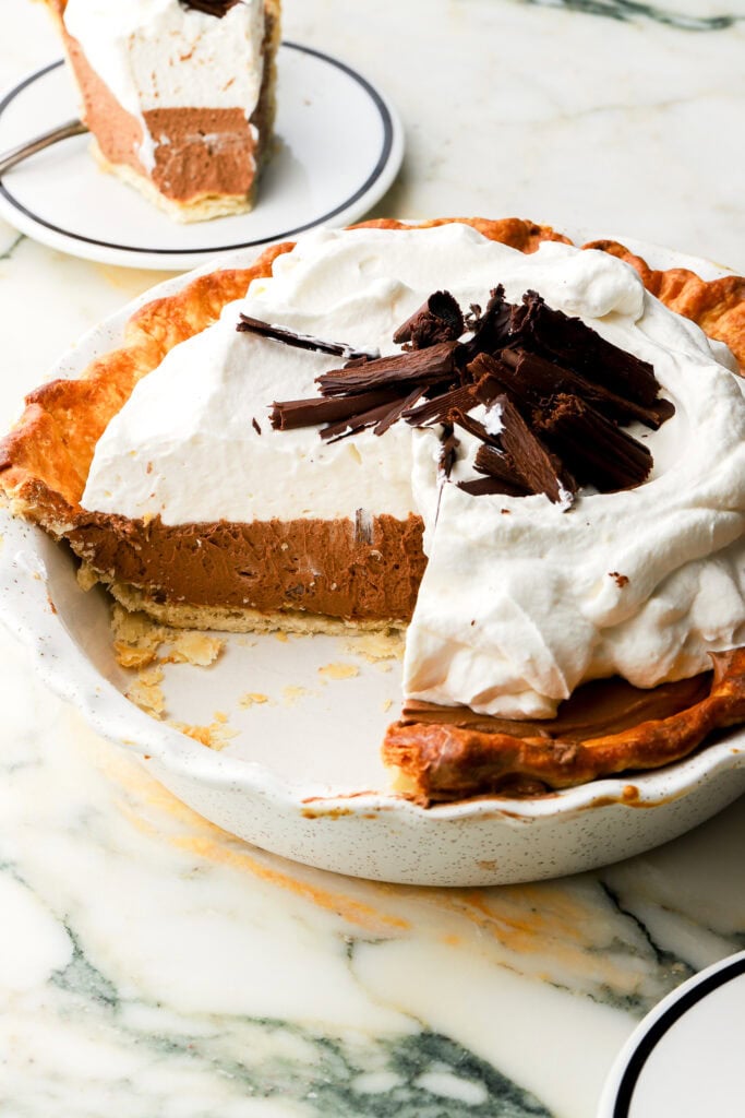 french silk pie in a pie dish with a couple slices missing and a plate with a slice behind it