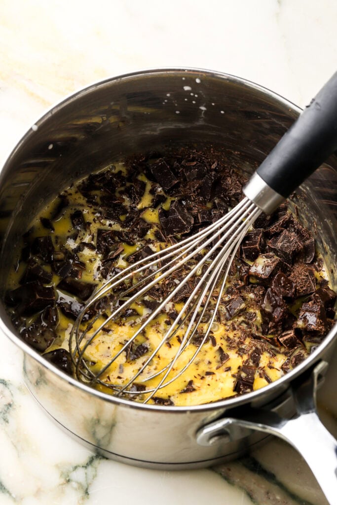 chocolate chunks added to egg yolk mixture in saucepan with a whisk