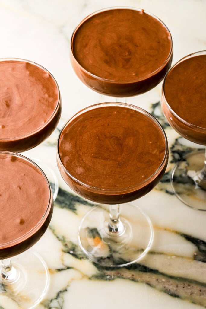 finished chocolate mousse poured into coupe glasses on a marble countertop