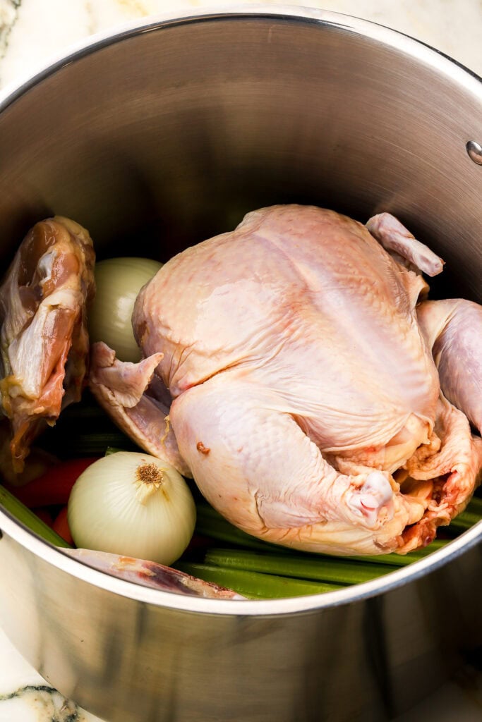 whole chicken sitting on top of the vegetables in the pot