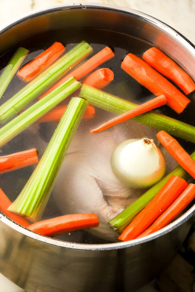 pot filled with vegetables, chicken and water to the top