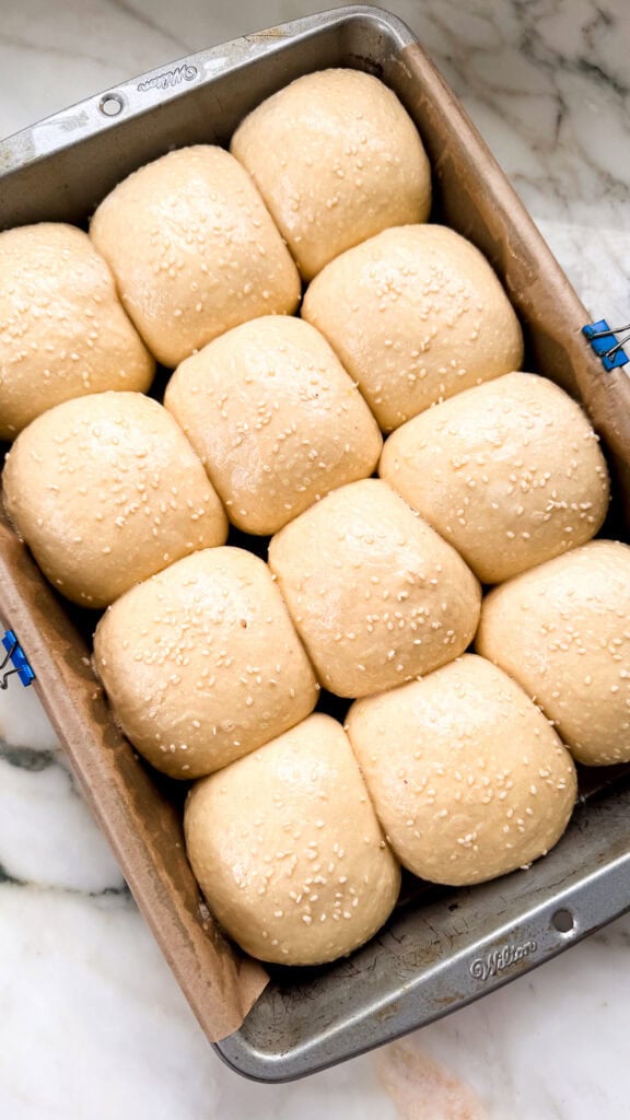 proofed dough balls brushed with egg wash and topped with sesame seeds before baking