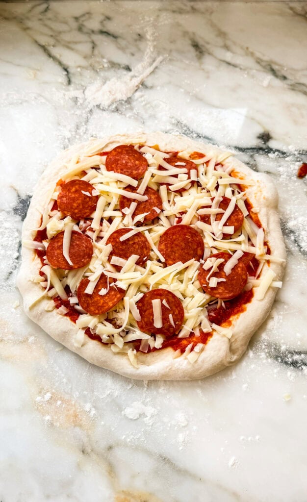 toppings and cheese added to hand stretched pizza dough before baking