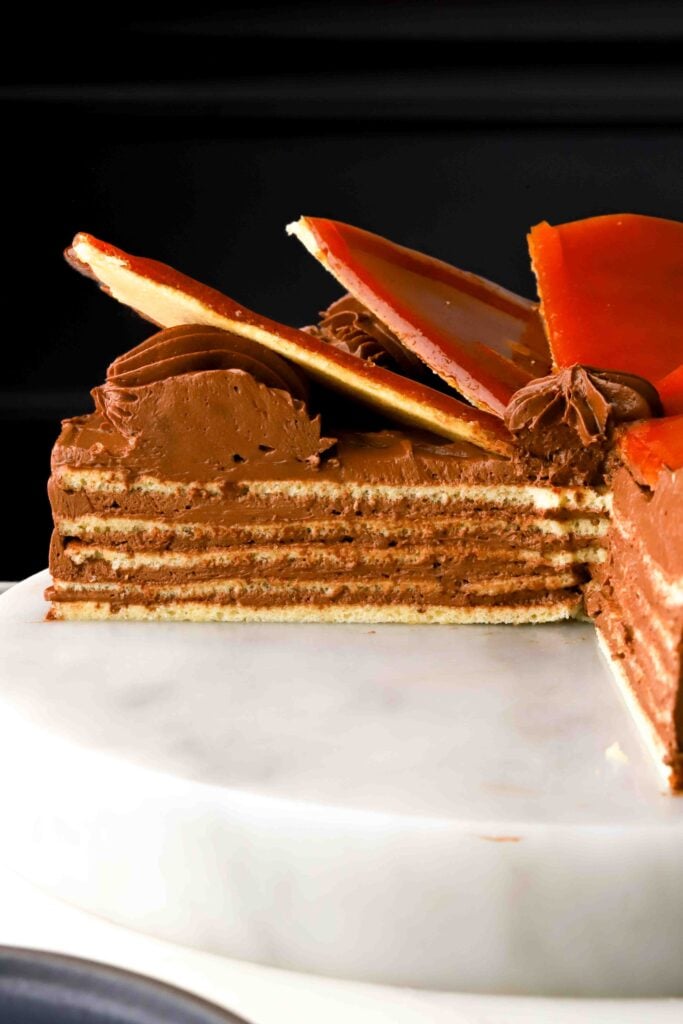 dobos topped with caramel triangles - several slices removed showing the inside of the cake with a black background