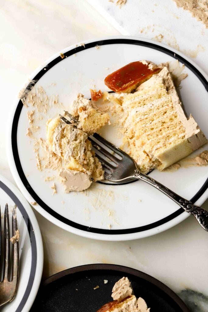 slice of coffee dobos on a plate with bites taken out and fork on it