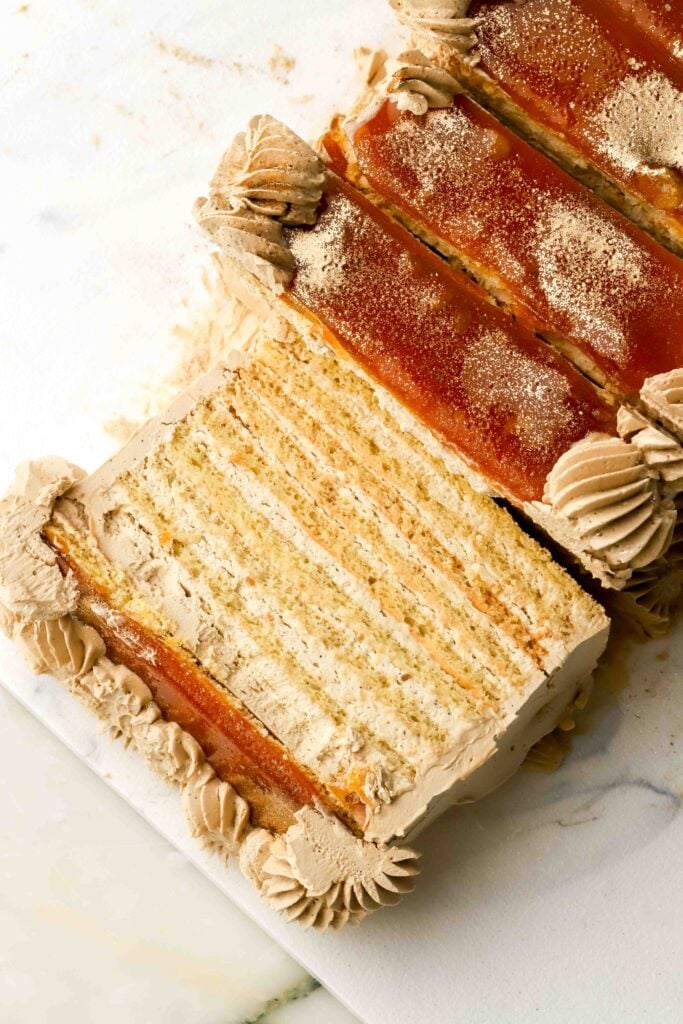 close up of brown butter layered sponge cake with espresso cream and caramelized sugar topping. slice fallen to the side next to other slices