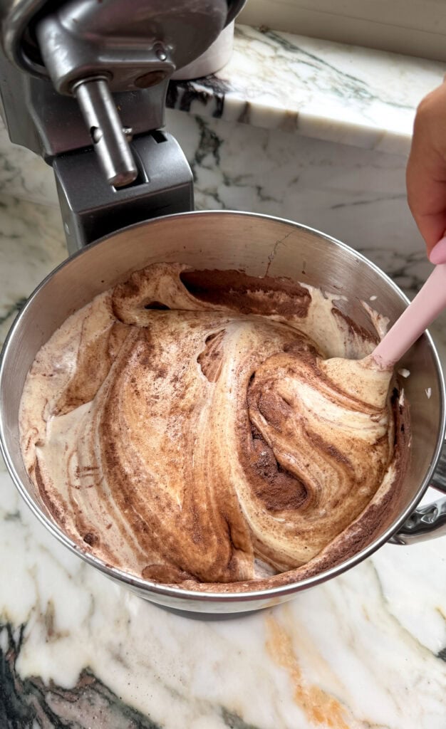 dry ingredients getting folded into the batter in a mixing bowl