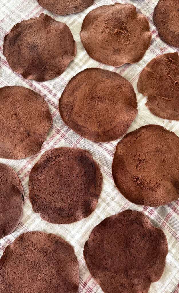 thin layers of chocolate sponge cake laid out on a tablecloth to cool 